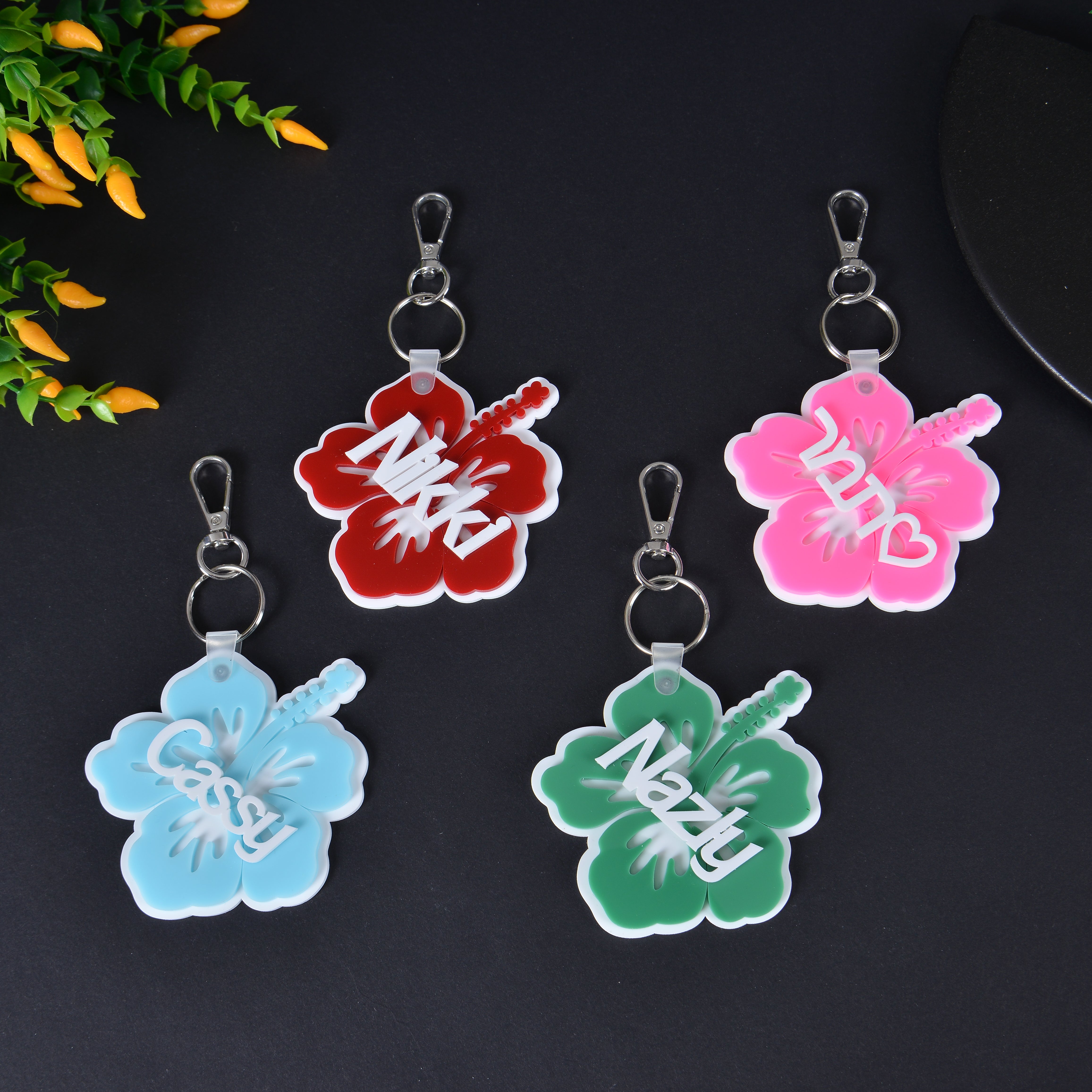 Pendantify personalized floral keychain featuring custom name overlays on colorful acrylic hibiscus flower silhouettes.