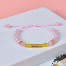 Pink rose quartz bead bracelet featuring custom name engraved gold bar charm.