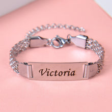 Silver custom engraved nameplate bracelet featuring script name Victoria connected to dual-strand metallic chain links.