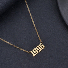 Gold personalized birth year necklace featuring a custom year in bold Old English font.