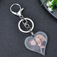 A silver heart-shaped keychain with a photo of a mother and child. The keychain has a silver split ring and a silver lobster clasp.