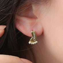 Woman wearing personalized baby foot stud earrings with a custom engraved baby name.
