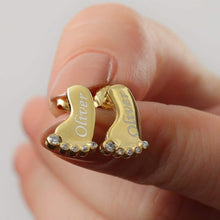 Close-up of personalized baby feet earrings showing the engraved name detail and crystal accents.