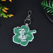 Green acrylic flower keyring customized with white overlay script name Nazly and metal swivel lobster clasp.