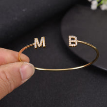 Close-up of gold CZ initial letter charm on open cuff