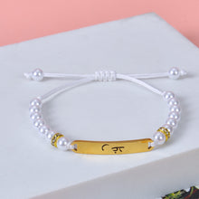 Close-up view of gold engraved plate on custom pearl bead adjustable sliding knot bracelet.