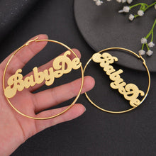 Large gold custom wire hoop earrings with bold cursive nameplate Dadrian centered inside the circle.