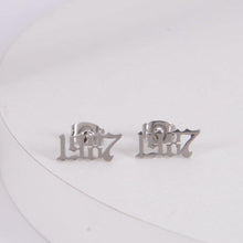 A pair of silver stud earrings with the number 1997 in a stylized font.