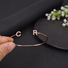 Close-up of rose gold CZ initial letter charm on open cuff