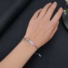 An image of a person wearing silver name bracelet with flower charm