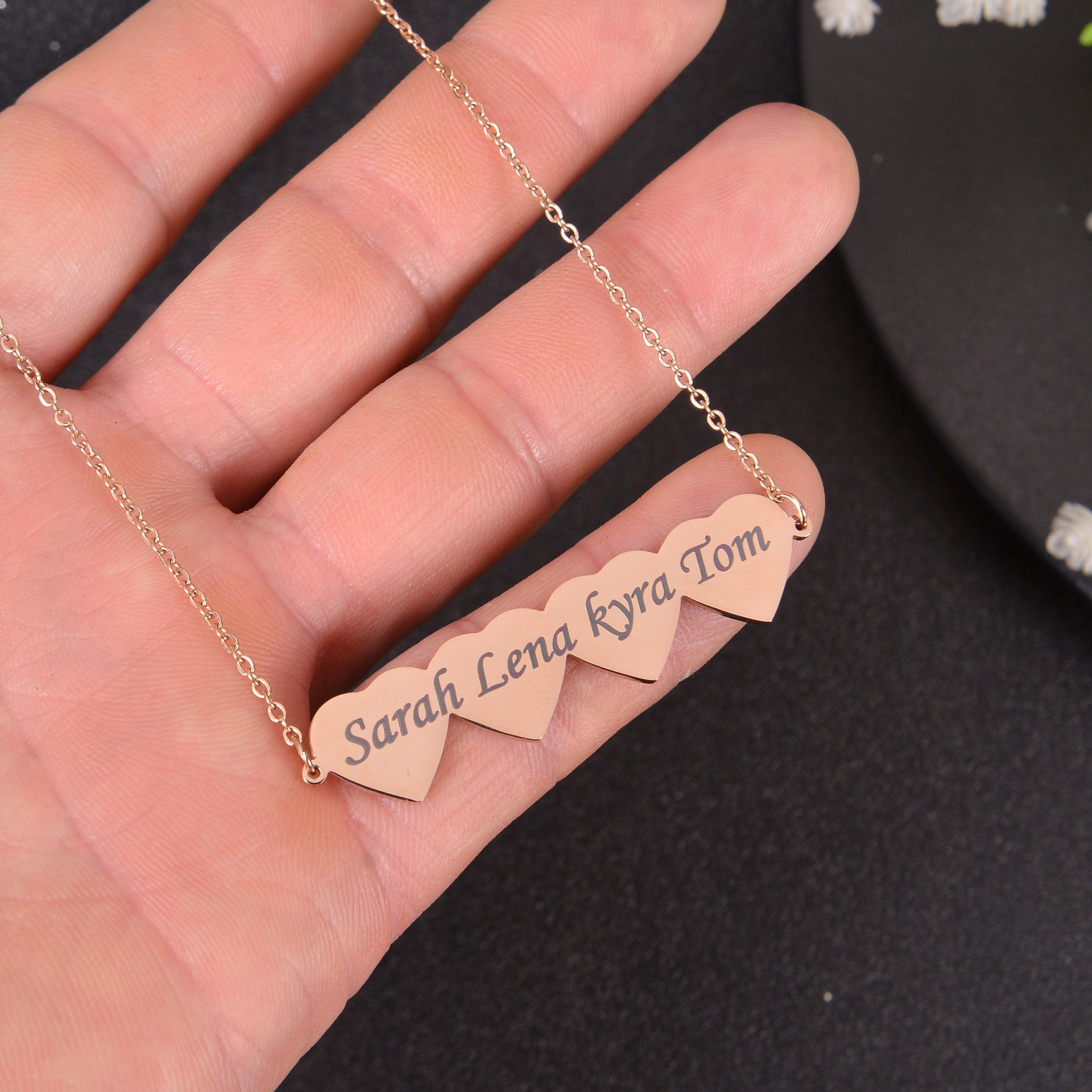 Close-up view of rose gold joined hearts pendant showing laser-engraved cursive script family names.