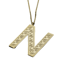 Large gold initial pendant laid flat on jewelry display