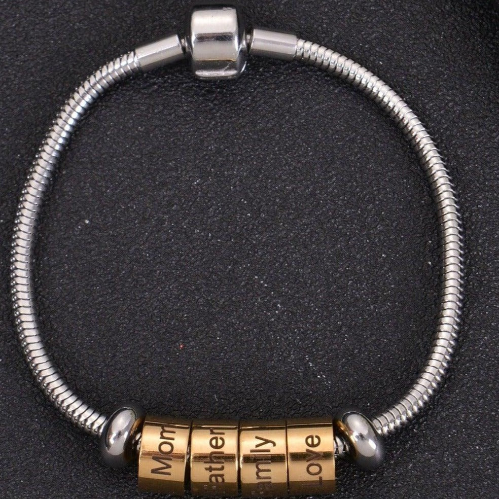 Gold personalized cylinder name beads grouped together on silver snake chain bracelet with secure clasp.