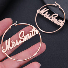 Medium rose gold custom wire hoop earrings with bold cursive nameplate Mrs. Smith centered inside the circle.
