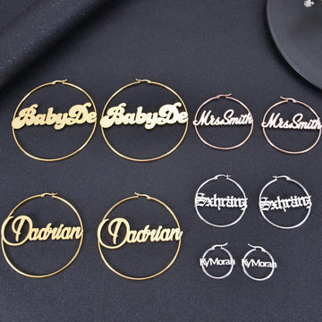 Display of custom script and Old English name hoop earrings in gold, silver, and rose gold on dark textured backdrop.