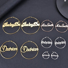 Display of custom script and Old English name hoop earrings in gold, silver, and rose gold on dark textured backdrop.