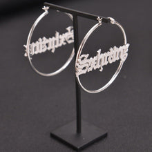 Small silver custom script name hoop earrings featuring modern cursive nameplate KyMorah centered inside.