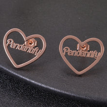 Rose gold personalized heart stud earrings featuring custom cursive script nameplate Pendantify suspended inside heart border.