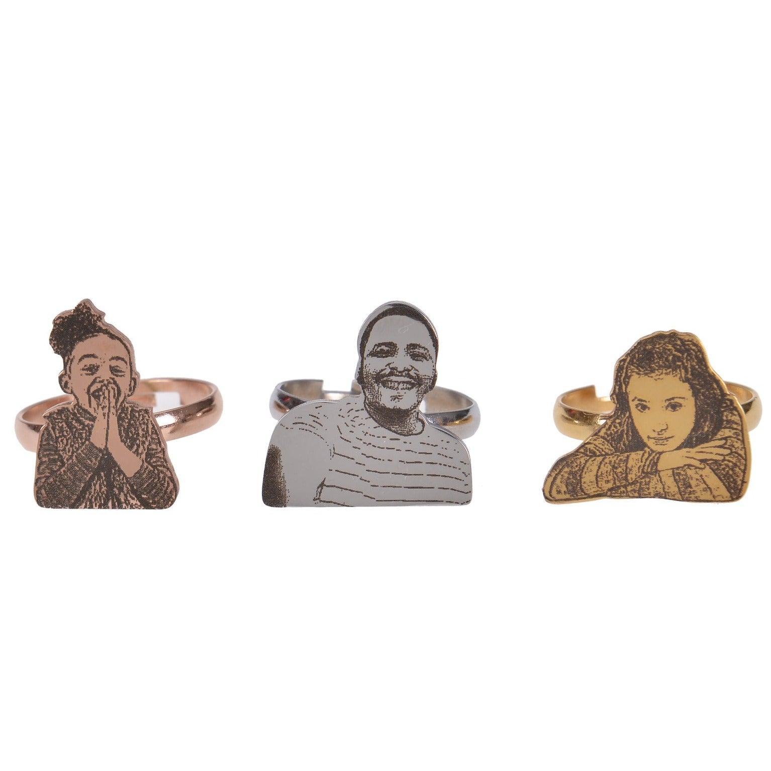Three silver rings with engraved images of people. The rings are on a white background.