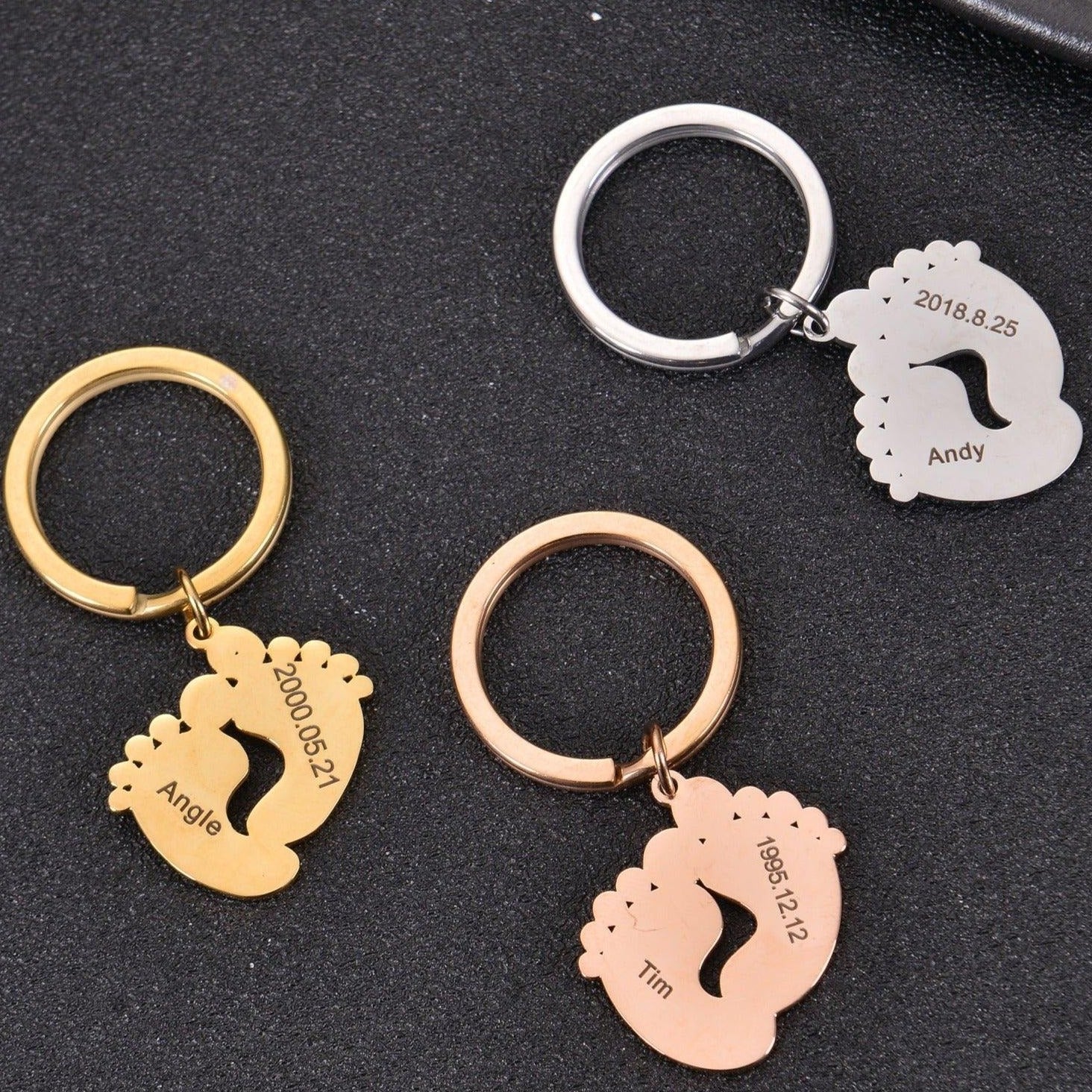 Three personalized baby footprint keychains shown together in Silver, Gold, and Rose Gold finishes.