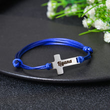 Close-up of engraved name on cross bracelet charm