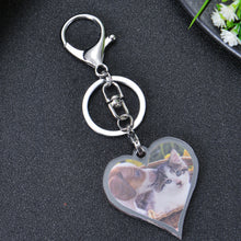 Silver heart-shaped keychain with a photo of a dog and cat. The keychain has a silver ring and a silver clasp.