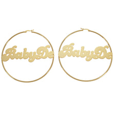 Large gold custom script name hoop earrings featuring retro cursive typography reading BabyDe across the center.