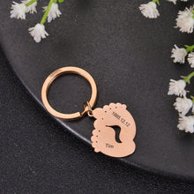 Rose gold personalized baby footprint keychain engraved with a baby's name and special date.