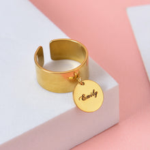 Gold personalized adjustable cuff ring with a dangling round disc charm custom engraved with cursive name Emily.