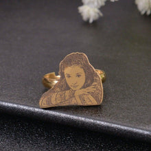 A gold ring with a photo of a person engraved on the face of the ring.