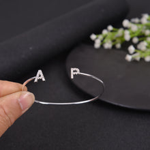 Close-up of silver CZ initial letter charm on open cuff