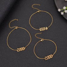 Close-up of a personalized Old English number charm anklet showing the custom engraved year.